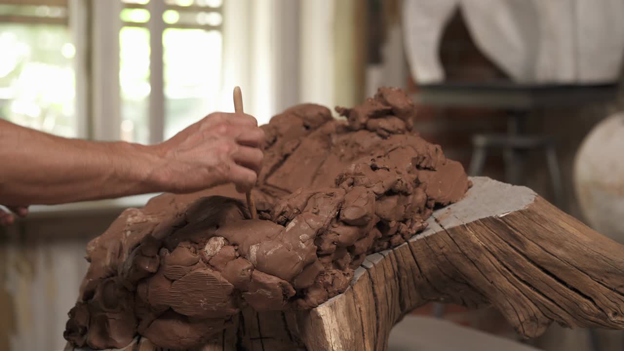 un primer plano de escultores masculinos tomando y moldeando arcilla para crear esculturas de cerámica en un estudio de arte profesional