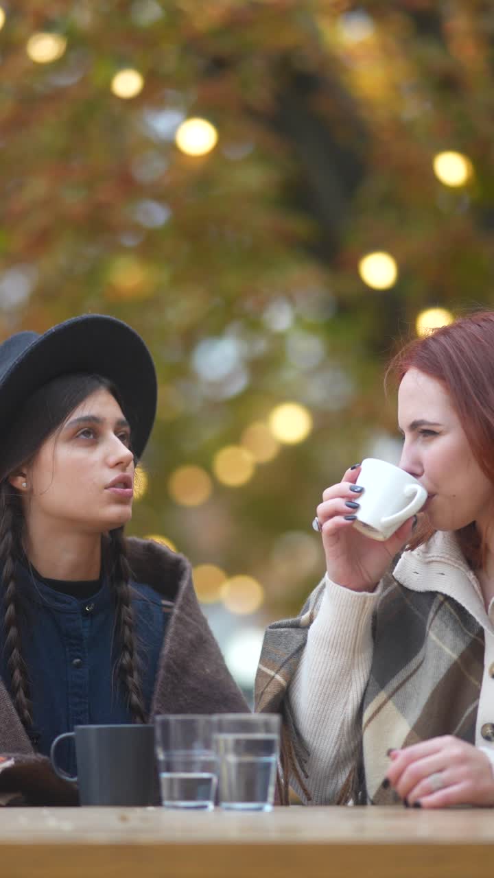 두 명의 여성이 야외에서 커피를 즐기고 있습니다.