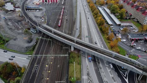 Trenes-Que-Viajan-Por-La-Vía-Que-Va-Al-Este-De-Estocolmo-Con-Tráfico-En-La-Carretera-En-Gotemburgo,-Suecia