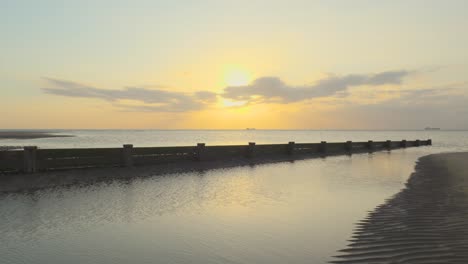 Reveal-of-ship-on-horizon-on-calm-sea-during-sunset-in-slow-motion-at-Fleetwood,-Lancashire,-UK