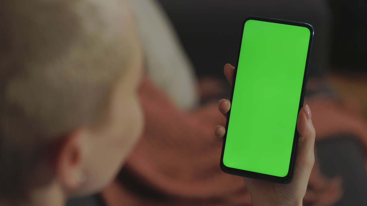 Woman holding a smartphone with a green screen