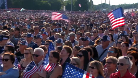 patriotic crowd waving american flags at an outdoor event