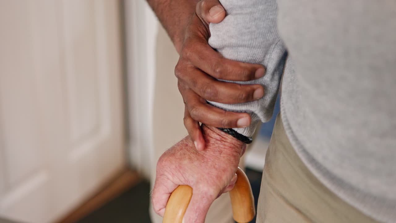 Close-up of hands holding a walking cane, representing intergenerational care and support for the elderly