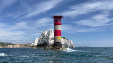 paisaje tomado desde un barco que muestra un faro en la costa de la isla de wight junto a los famosos acantilados de las agujas