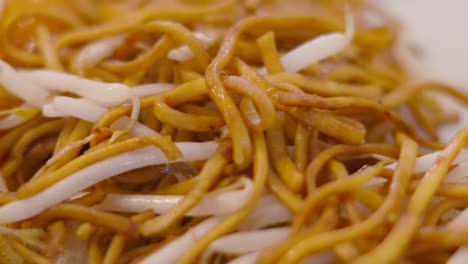 slow moving overview shot of freshly cooked chinese chow mein noodles with beansprouts. oriental takeaway takeout style food