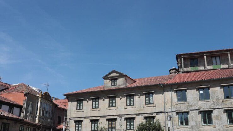 Vecchio edificio in pietra con tetto in tegole rosse sotto un cielo azzurro limpido a Pontevedra, Galizia, Spagna.
