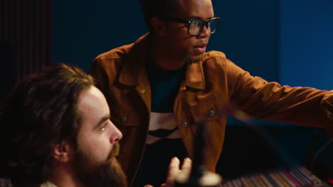 musician and producer work on soundboard pads at professional studio