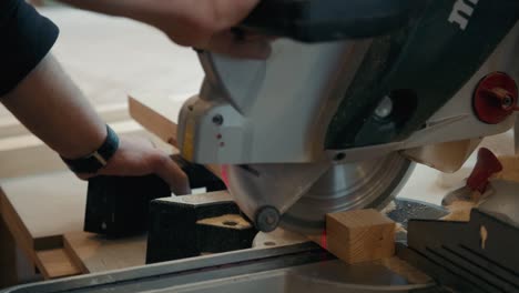 close up of carpenter's hands cutting wood with table saw in workshop, craftsman furniture