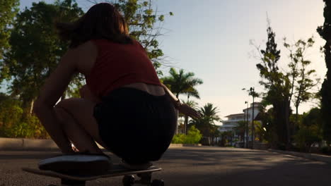 slow motion captures a young woman riding a longboard near palm trees, donning shorts and sneakers in the summer scene