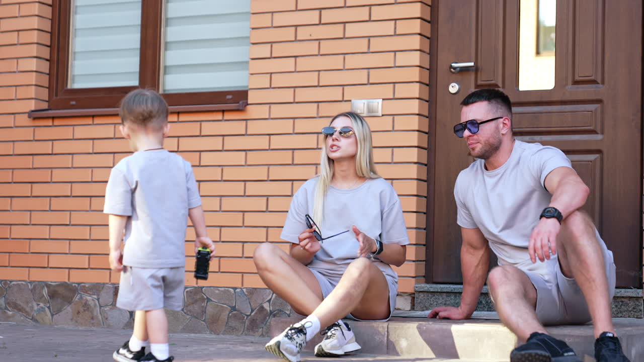 Family having fun outside. A family sits on steps of a home, interacting and enjoying their time while wearing matching outfits and sunglasses
