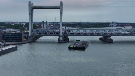 container barge passed under railway bridge across oude maas river, dordrecht, netherlands