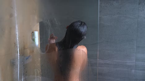 mujer lavándose el cabello en una ducha
