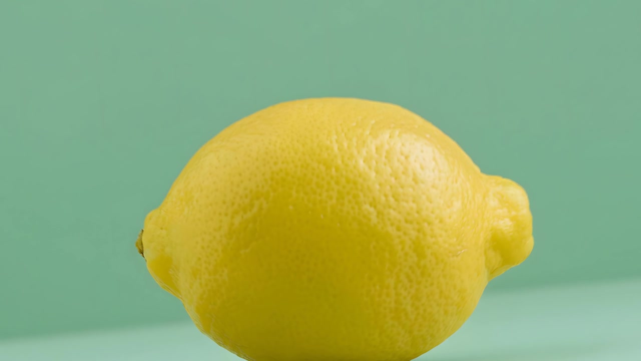 Primo piano di un limone giallo intero su sfondo turchese