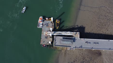 Sunny-Beaumaris-pier-aerial-view-relaxing-seaside-waterfront-tourist-attraction-Welsh-landmark-top-down-rising