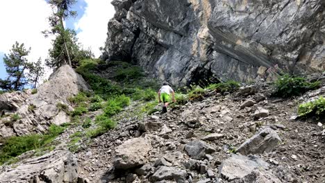 cute young boy climbing up some stones in the mountains