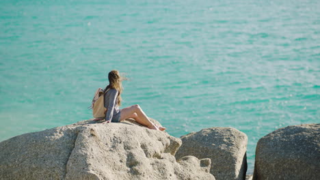 mujer, océano y roca mientras están de vacaciones