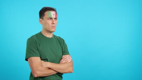 man with mexican flag painted looking away with serious expression