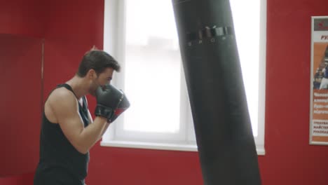 Sport-man-punching-boxing-bag-at-fight-training.-Kickboxer-training-in-fight-club