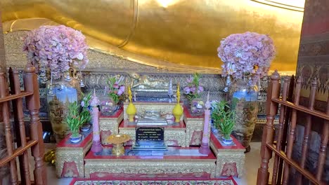 a serene view of the golden reclining buddha statue at wat pho, bangkok, showcasing intricate details and vibrant floral arrangements