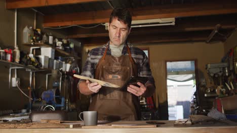 focused caucasian male knife maker in workshop preparing knife mold and using tablet