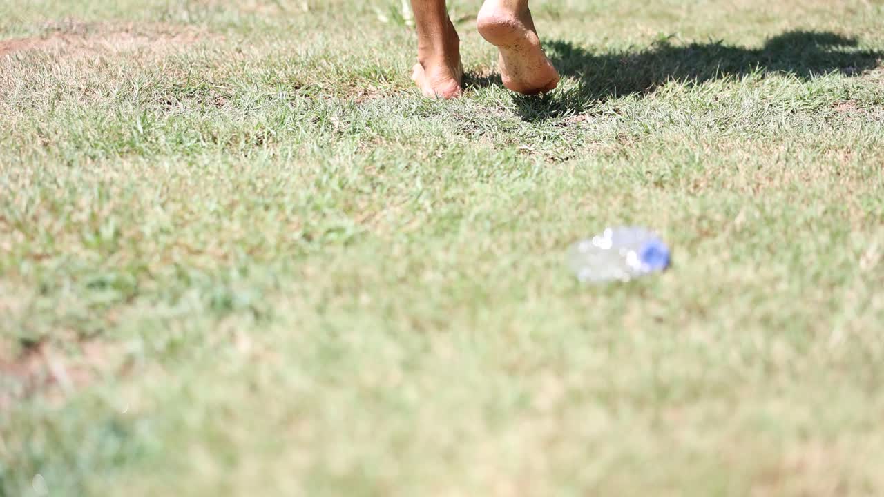 Plastic bottle littering on grass near feet