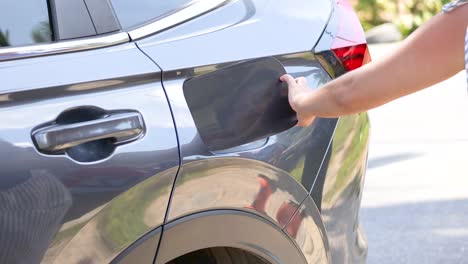 a person opens a car's fuel tank cap in bright daylight at khao rang viewpoint, phuket, thailand