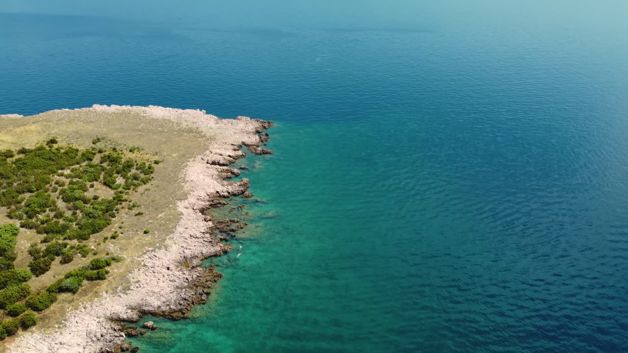 vista aérea giratoria de dos personas nadando en la playa de risika en la isla de krk en croacia