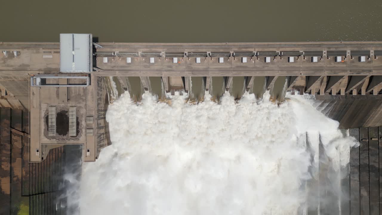 Aerial rises slowly from dramatic hydro dam releasing flood water