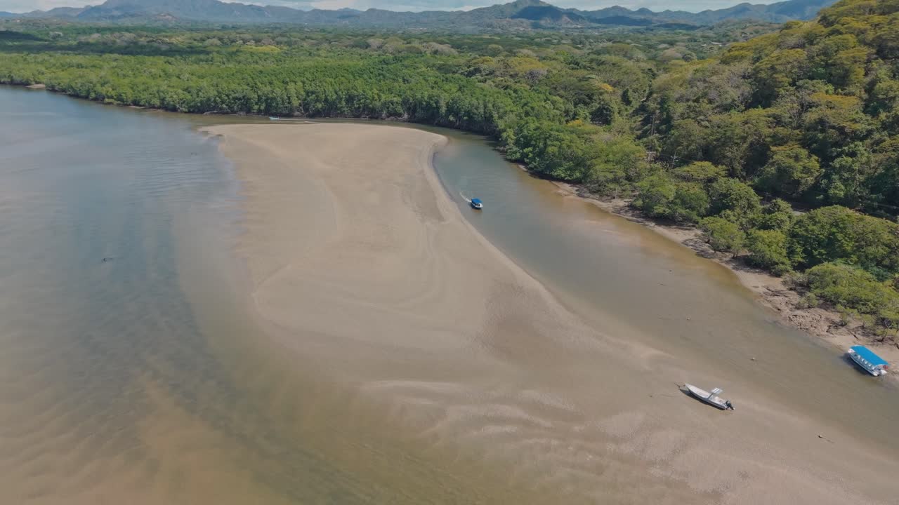 Drone zooming out revealing the estuary and sandbanks surrounded by green mangroves near Tamarindo