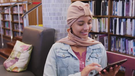 Asian-female-student-wearing-a-beige-hijab-sitting-and-using-a-tablet