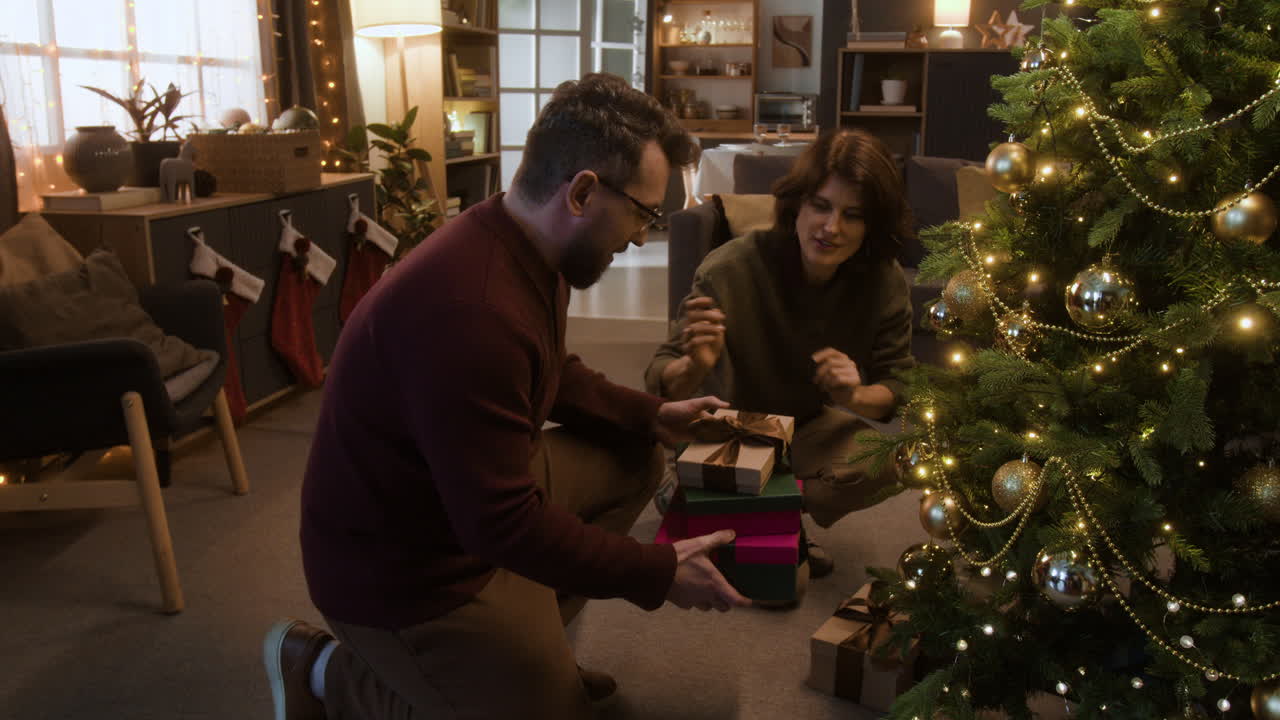 Couple Placing Gifts Under Christmas Tree