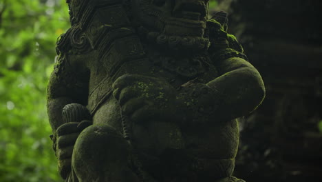 closeup of mossy balinese statue at sacred monkey forest sanctuary in bali, indonesia