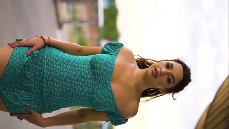 attractive-European-mixed-ethnicity-woman-walking-outdoor-with-a-short-Spanish-styled-dress-of-aqua-colour-looking-around-pure-innocence-in-her-20s-confident-steps-in-heels-vertical-cinematic-slowmo
