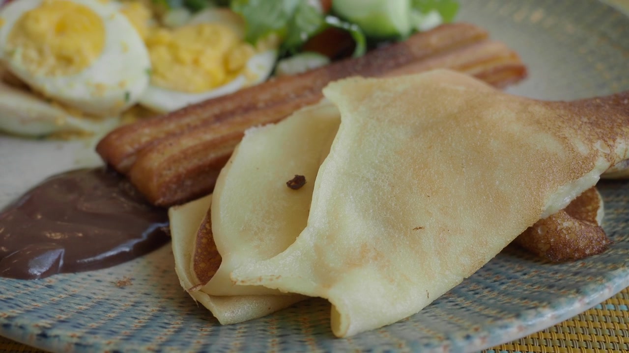 Delicious Breakfast Plate with Crepes, Bacon, Eggs, and Salad