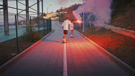 active young couple in love riding longboards with red signal fire in evening