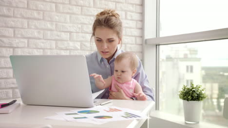 woman with baby not concentrated at work. business mother looking documents