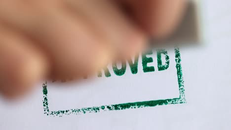 person puts on paper stamp approved closeup