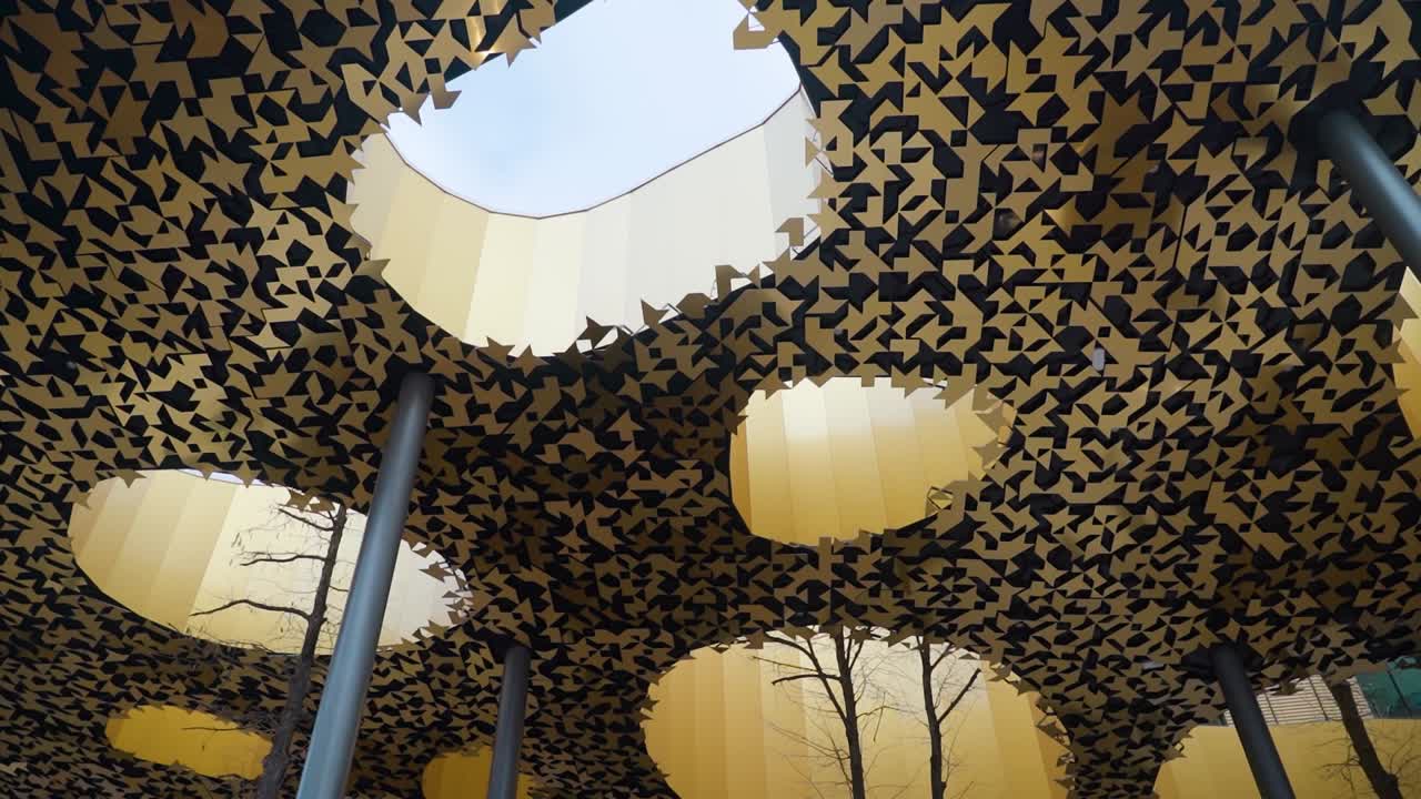 가리 음악의 집의 복잡한 황금색 지붕 패턴의 클로즈업, 절단 된 모양과 주변 나무 가지와 함께