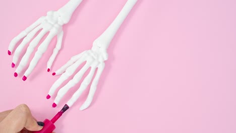 la aplicación de esmalte de uñas rosa en los brazos esqueléticos. manicure creativo stop motion