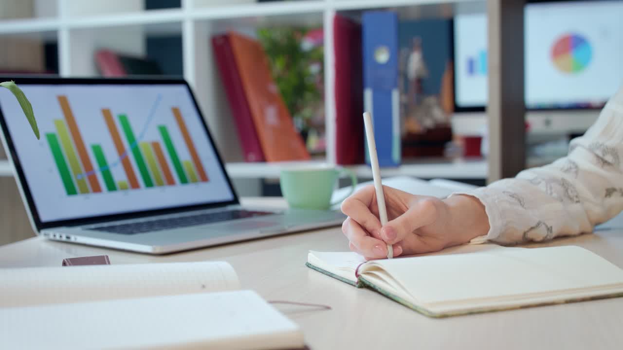 mujer escribiendo a mano en un cuaderno en el espacio de trabajo de una empresa moderna