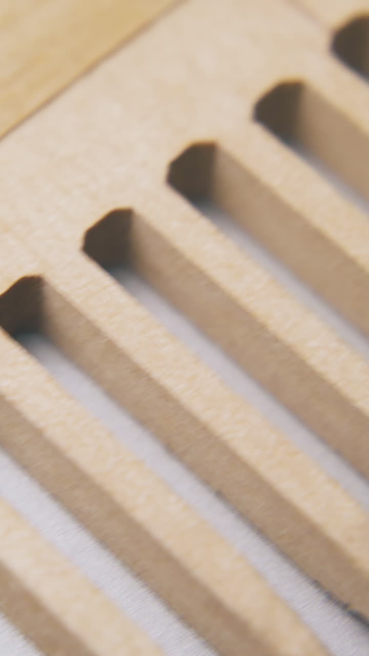 motion along beautiful handmade wooden comb lying on light grey surface extreme close view