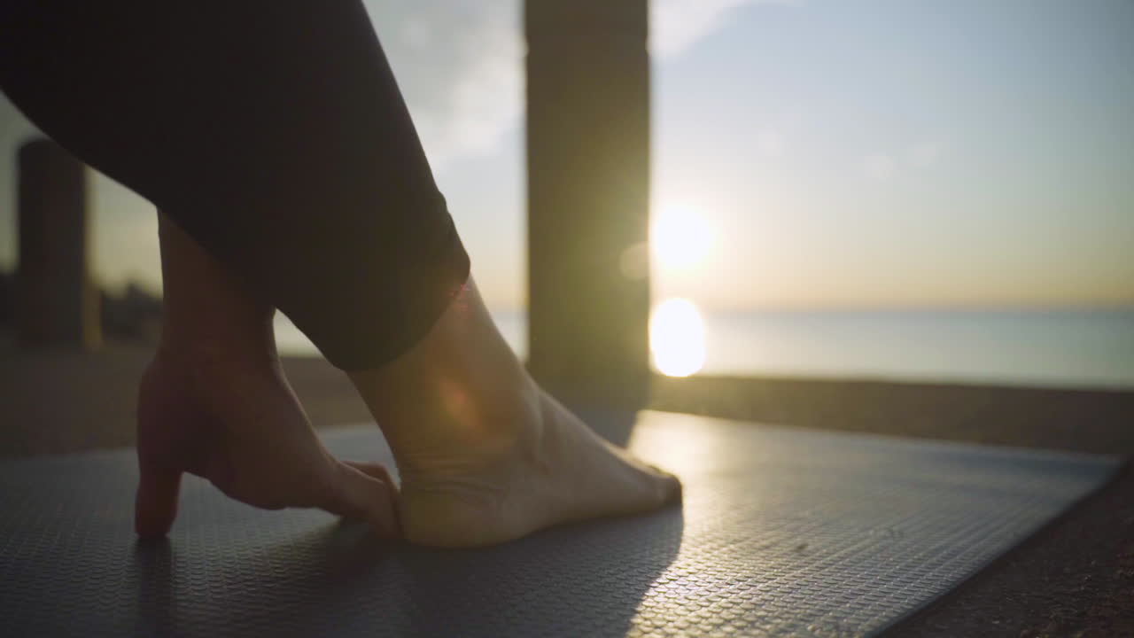 Woman doing yoga at sunrise by the water. Slow Motion.