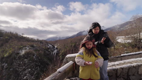 mother and daughter enjoying snowy mountain viewpoint in winter landscape, family travel