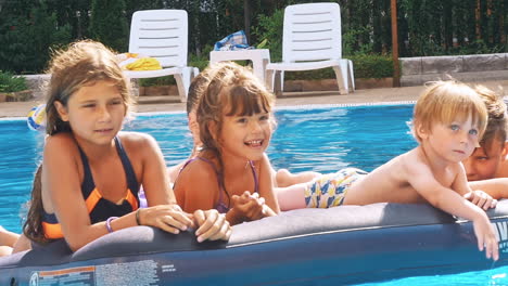 smiling, happy children on a float in a swimming pool.