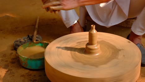 pottery - skilled wet hands of potter shaping the clay on potter wheel. pot, vase throwing. manufacturing traditional handicraft indian bowl, jar, pot, jug. shilpagram, udaipur, rajasthan, india