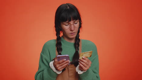 mujer joven que usa tarjeta bancaria de crédito y teléfono inteligente mientras transfiere dinero para compras en línea