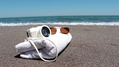 cámara con playa acostada y gafas en la playa de arena