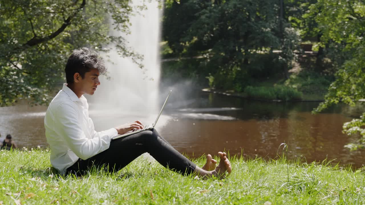 평화롭게 공원에서 자신의 노트북에서 작업하는 젊은 남자의 프로필 전체 shott