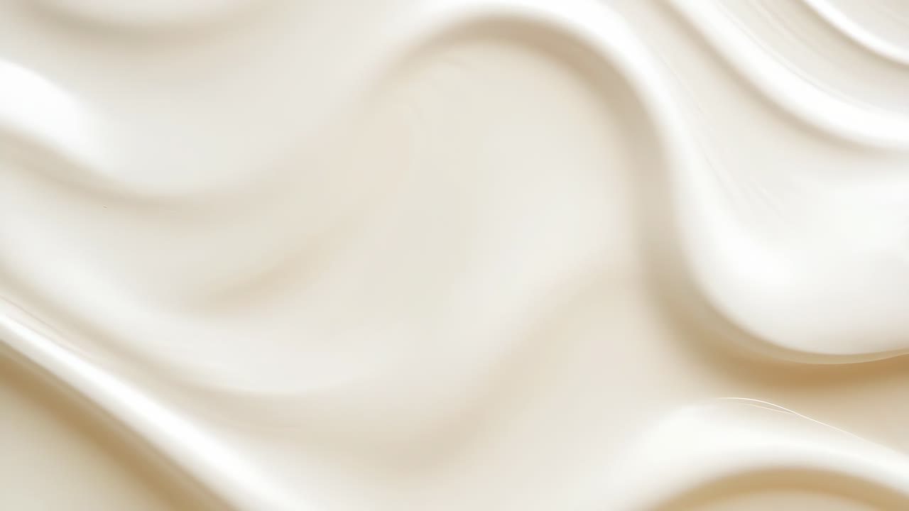 Detailní záběr z ptačí perspektivy na hladké, plynoucí vlny smetany. Abstraktní design evokuje uklidňující pocit