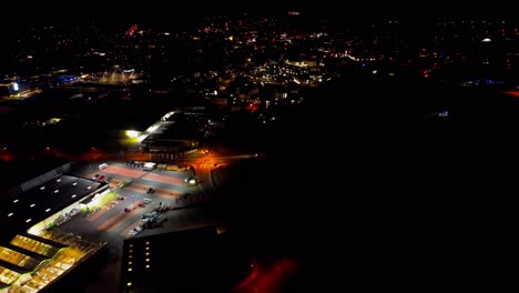 Aerial-View-Over-Lit-Gas-Station-and-Surrounding-Night-Cityscape